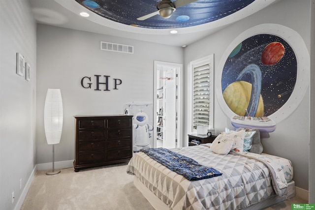 bedroom featuring ceiling fan, light colored carpet, and a raised ceiling