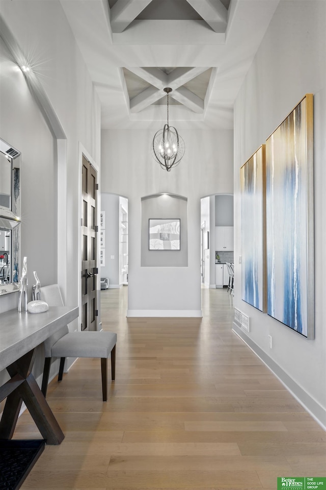 dining space featuring beamed ceiling, coffered ceiling, a notable chandelier, and light hardwood / wood-style floors