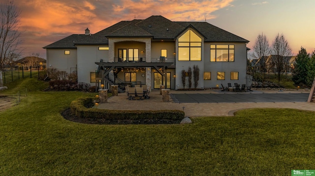 back house at dusk featuring a yard and a patio