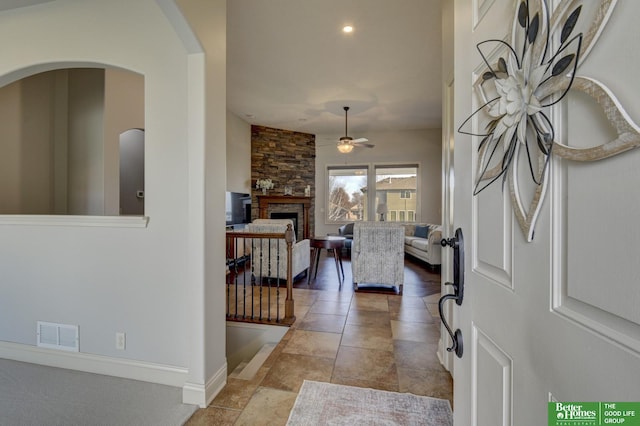 entrance foyer featuring ceiling fan and a stone fireplace