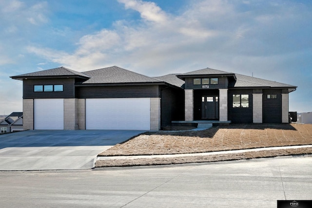 prairie-style home with a garage and central air condition unit