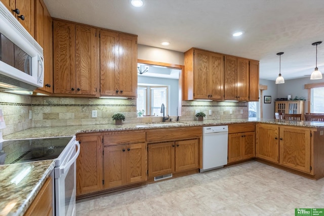 kitchen featuring tasteful backsplash, white appliances, decorative light fixtures, and sink