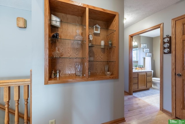 hallway featuring light hardwood / wood-style flooring and a textured ceiling