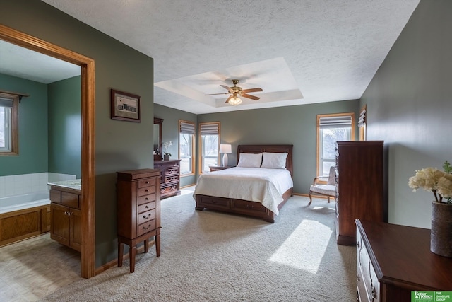 bedroom with a tray ceiling, a textured ceiling, light colored carpet, and ceiling fan