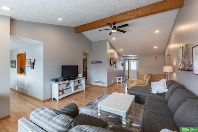 living room with ceiling fan, vaulted ceiling with beams, a textured ceiling, and light hardwood / wood-style flooring