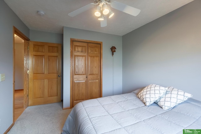 bedroom featuring light carpet, ceiling fan, and a closet