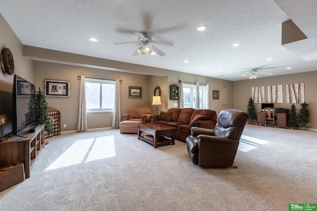 living room featuring ceiling fan, light colored carpet, and a textured ceiling