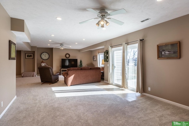 unfurnished living room with ceiling fan, light colored carpet, and a textured ceiling