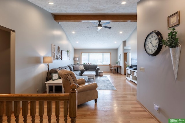 living room with lofted ceiling with beams, ceiling fan, a textured ceiling, and light hardwood / wood-style flooring