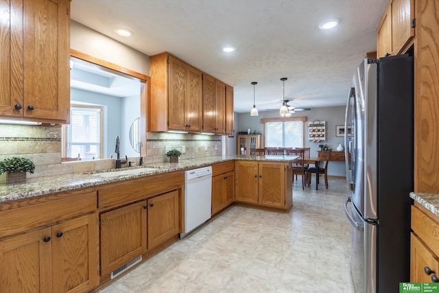 kitchen with sink, stainless steel refrigerator, white dishwasher, tasteful backsplash, and kitchen peninsula