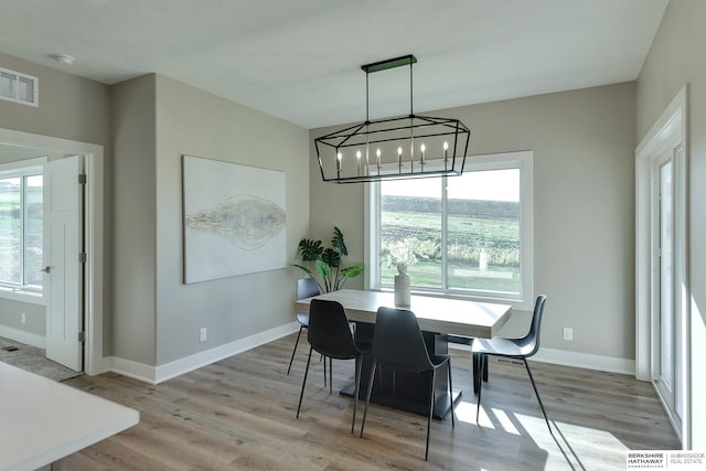 dining room with light hardwood / wood-style flooring and a notable chandelier