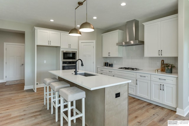 kitchen featuring built in microwave, sink, white cabinets, and wall chimney exhaust hood