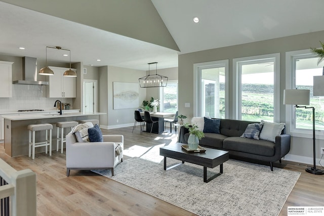 living room with light hardwood / wood-style flooring, high vaulted ceiling, and a healthy amount of sunlight