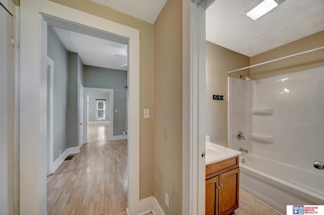 bathroom with washtub / shower combination, vanity, and hardwood / wood-style floors