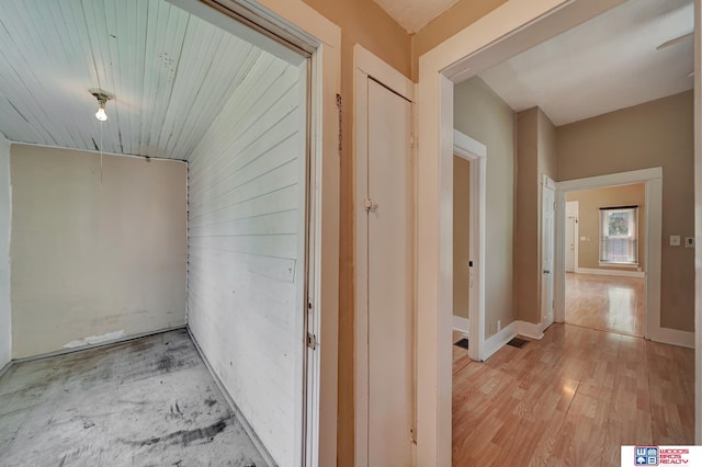 hallway with light hardwood / wood-style flooring and wooden ceiling