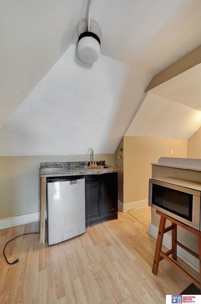 kitchen with sink, vaulted ceiling, dishwasher, and light wood-type flooring