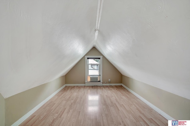 additional living space with vaulted ceiling, cooling unit, and light wood-type flooring