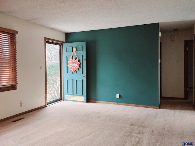 spare room featuring a textured ceiling and carpet