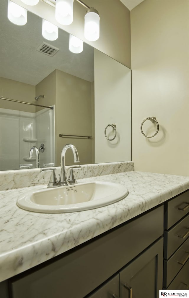 bathroom featuring a shower and vanity