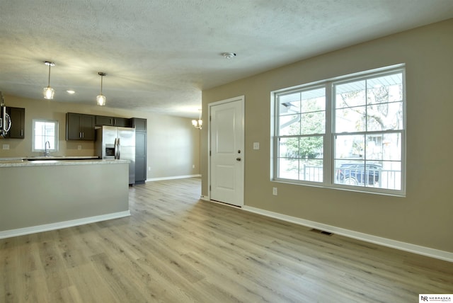 kitchen with pendant lighting, light hardwood / wood-style flooring, an inviting chandelier, stainless steel refrigerator with ice dispenser, and dark brown cabinetry