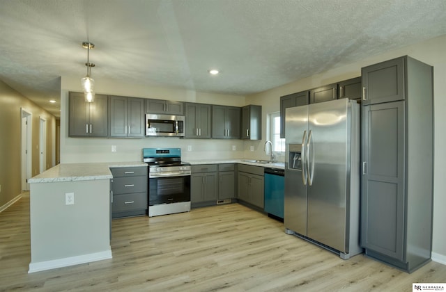 kitchen featuring sink, decorative light fixtures, light wood-type flooring, appliances with stainless steel finishes, and gray cabinets