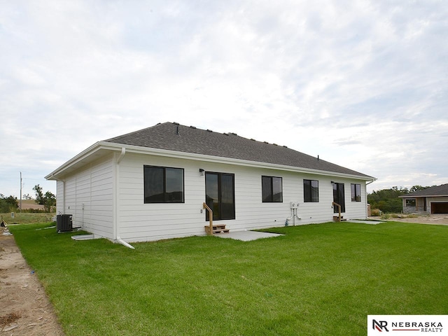 rear view of property with a lawn and central air condition unit