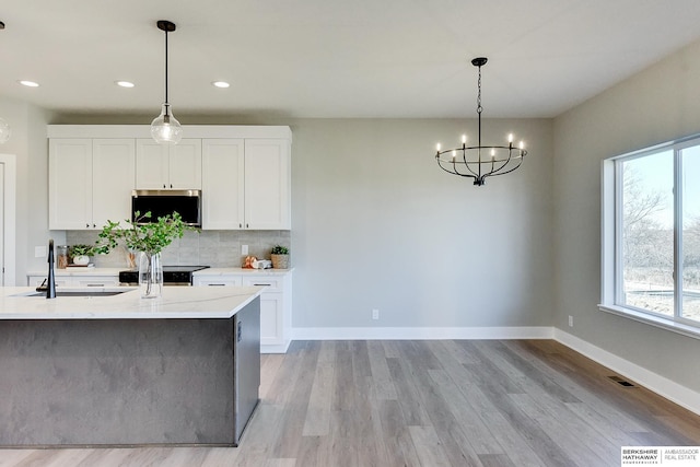 kitchen with plenty of natural light, pendant lighting, white cabinets, and light hardwood / wood-style flooring