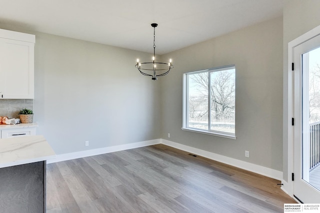 unfurnished dining area with a notable chandelier and light wood-type flooring