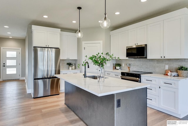 kitchen with sink, a center island with sink, appliances with stainless steel finishes, decorative backsplash, and white cabinets