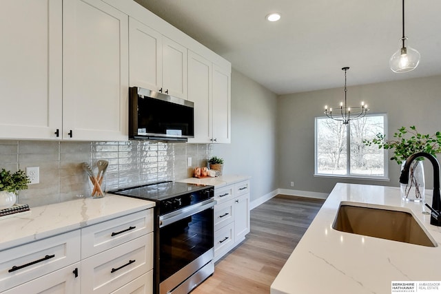 kitchen with range with electric cooktop, white cabinetry, light stone countertops, and sink