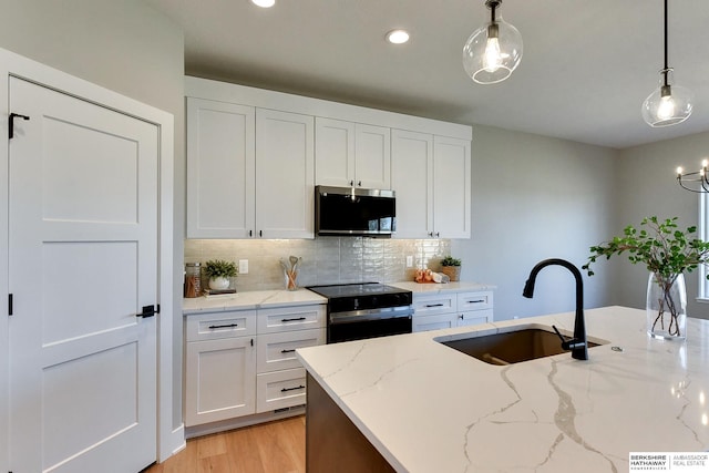 kitchen with black electric range oven, sink, hanging light fixtures, and white cabinets