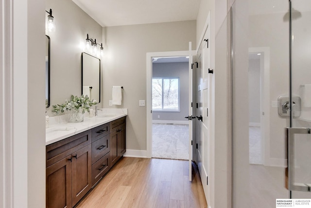 bathroom with hardwood / wood-style flooring, vanity, and a shower with shower door