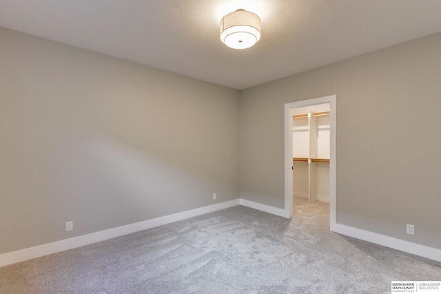 unfurnished bedroom with a spacious closet, light colored carpet, and a closet