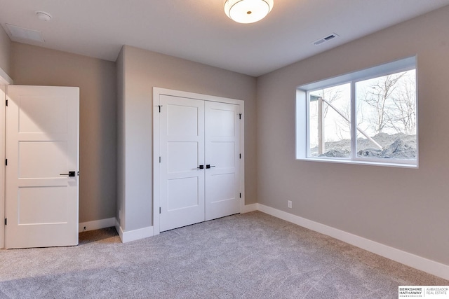 unfurnished bedroom with light colored carpet and a closet