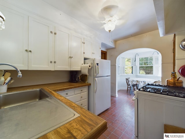 kitchen with white cabinetry, butcher block countertops, and white appliances