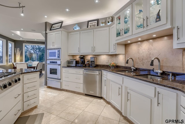 kitchen featuring white cabinetry, appliances with stainless steel finishes, dark stone countertops, and backsplash