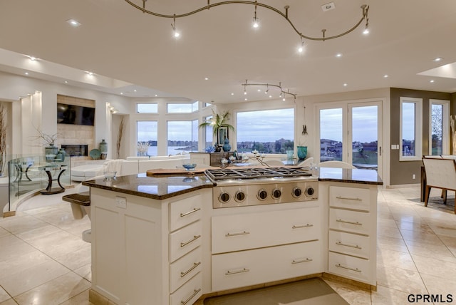 kitchen featuring white cabinetry, plenty of natural light, a kitchen island, dark stone counters, and stainless steel gas stovetop