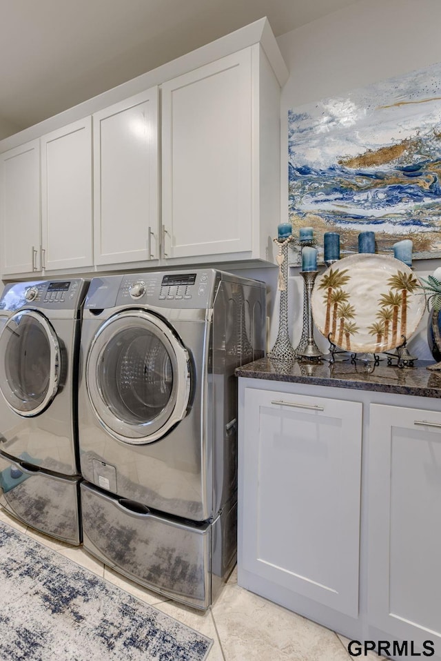 washroom with cabinets, light tile patterned floors, and washer and clothes dryer