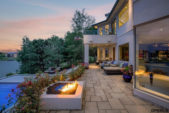 patio terrace at dusk with an outdoor living space with a fire pit