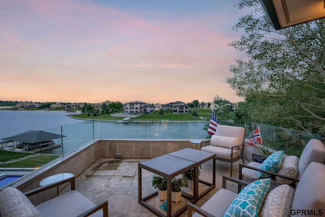 patio terrace at dusk with a water view, a balcony, and an outdoor hangout area