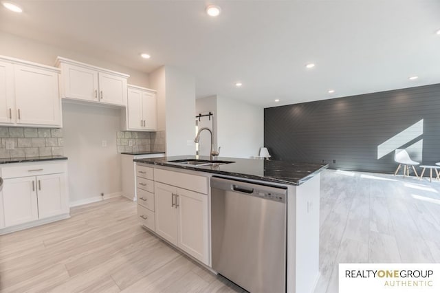 kitchen featuring sink, dishwasher, white cabinetry, backsplash, and dark stone countertops