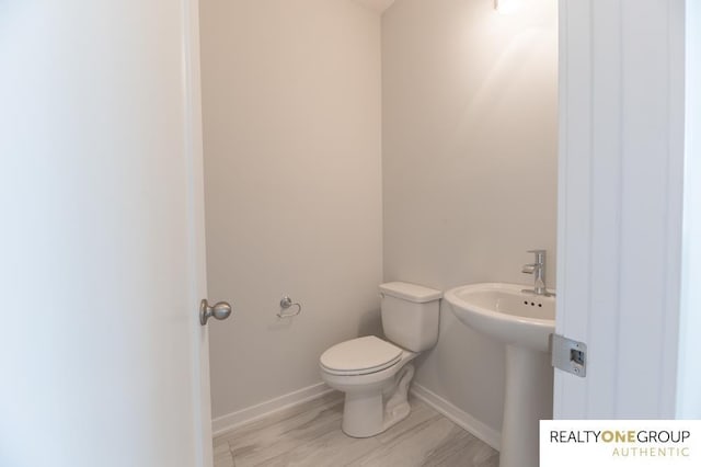 bathroom with wood-type flooring, toilet, and sink