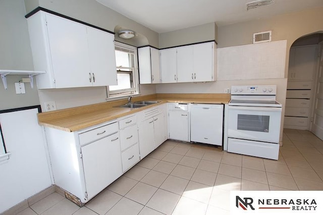 kitchen with sink, white appliances, light tile patterned floors, and white cabinets