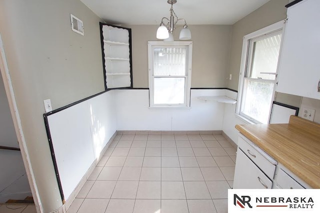 unfurnished dining area featuring an inviting chandelier and light tile patterned floors