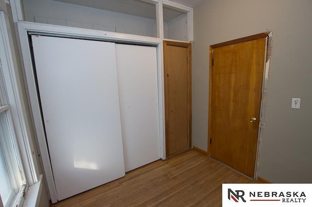 unfurnished bedroom with a closet and light wood-type flooring