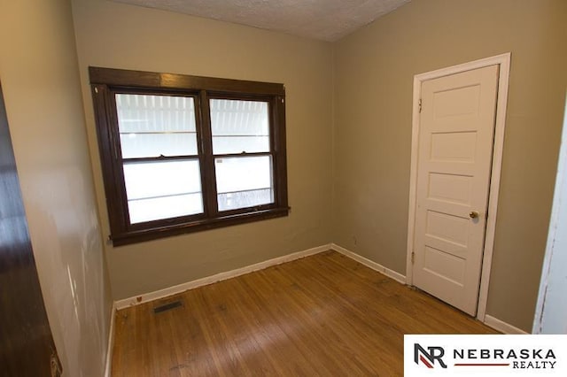 unfurnished room with hardwood / wood-style flooring and a textured ceiling