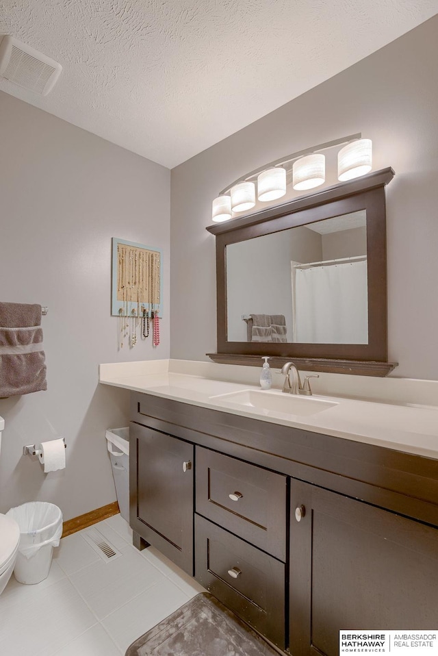 bathroom featuring vanity, tile patterned floors, a textured ceiling, and toilet