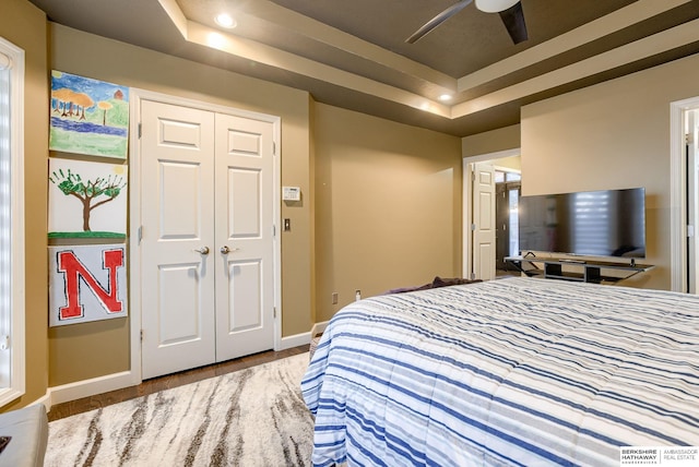 bedroom featuring a closet, ceiling fan, and a tray ceiling