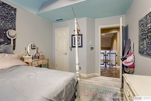 bedroom with lofted ceiling and light hardwood / wood-style floors