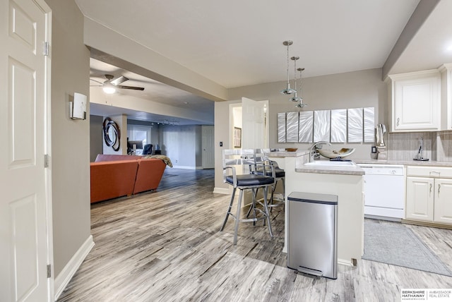 kitchen featuring pendant lighting, sink, white cabinets, decorative backsplash, and white dishwasher